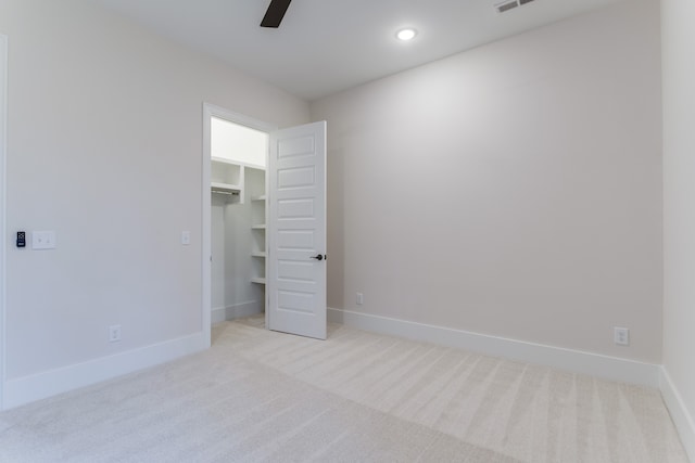 unfurnished bedroom featuring ceiling fan, a closet, light carpet, and a spacious closet