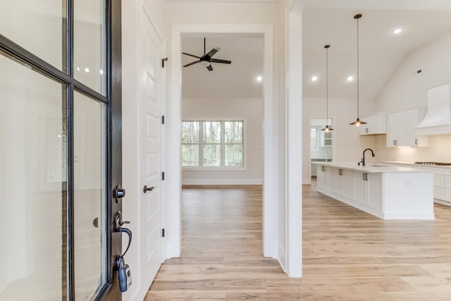 kitchen with cooktop, hanging light fixtures, custom range hood, and light hardwood / wood-style floors