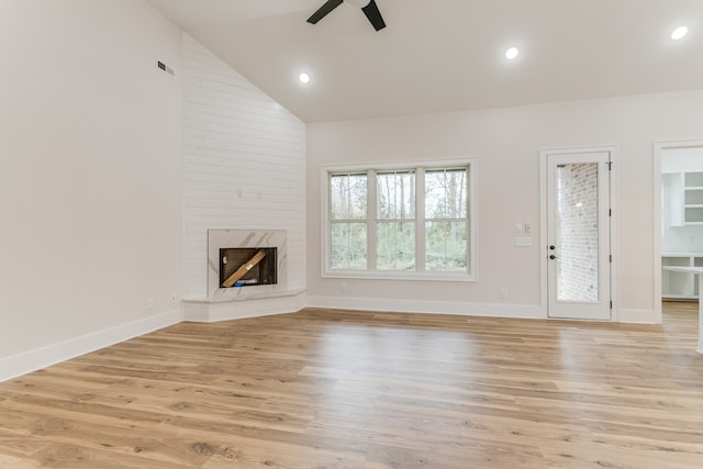 unfurnished living room with ceiling fan, light wood-type flooring, a fireplace, and high vaulted ceiling