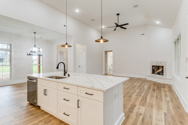 kitchen with stainless steel dishwasher, sink, light hardwood / wood-style floors, white cabinetry, and hanging light fixtures