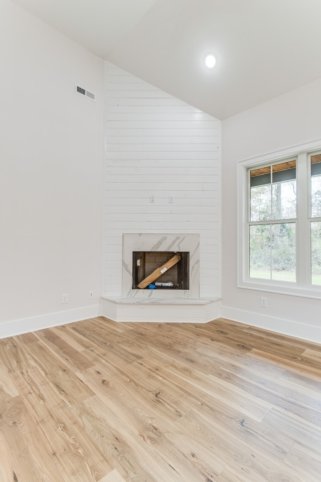 unfurnished living room with light wood-type flooring and a premium fireplace