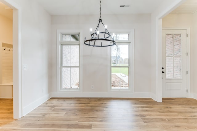 unfurnished dining area with light hardwood / wood-style flooring and a notable chandelier