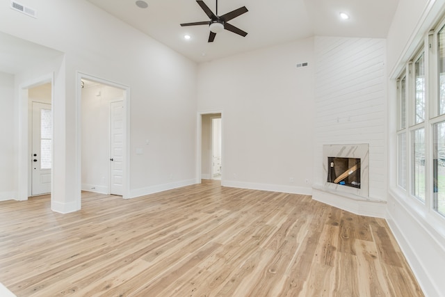 unfurnished living room featuring a fireplace, ceiling fan, light hardwood / wood-style flooring, and high vaulted ceiling