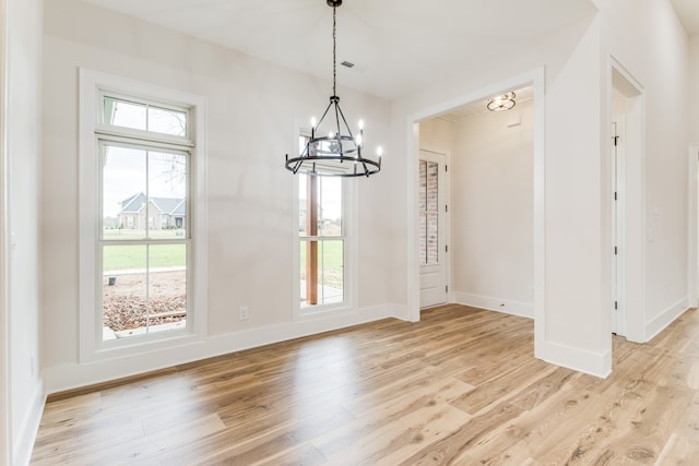 unfurnished dining area with a chandelier, plenty of natural light, and light hardwood / wood-style floors