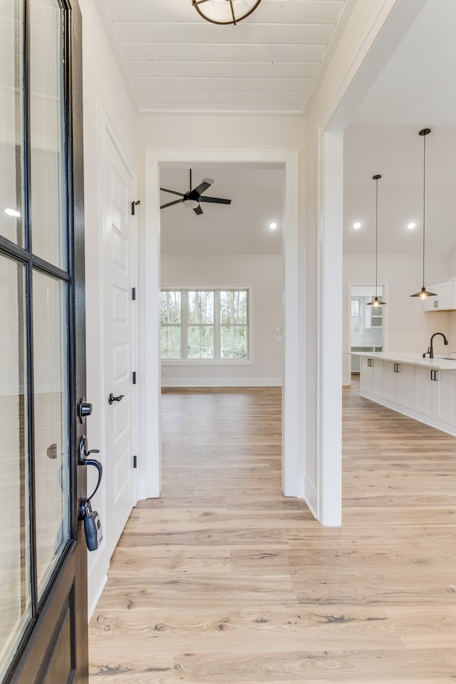 interior space with ceiling fan, sink, crown molding, and light wood-type flooring