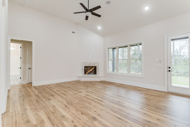 unfurnished living room with a large fireplace, light hardwood / wood-style flooring, and high vaulted ceiling