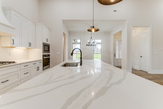 kitchen with pendant lighting, dark wood-type flooring, sink, light stone countertops, and appliances with stainless steel finishes