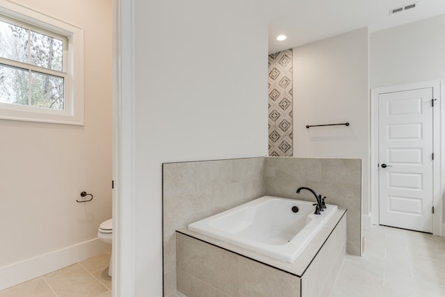 bathroom with tile patterned floors, toilet, and tiled tub