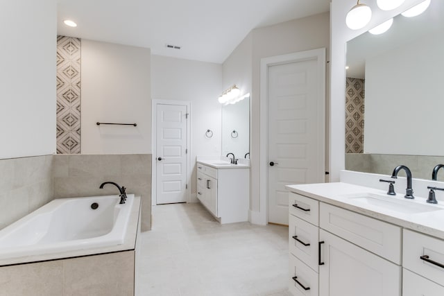 bathroom featuring tile patterned floors, vanity, and tiled bath