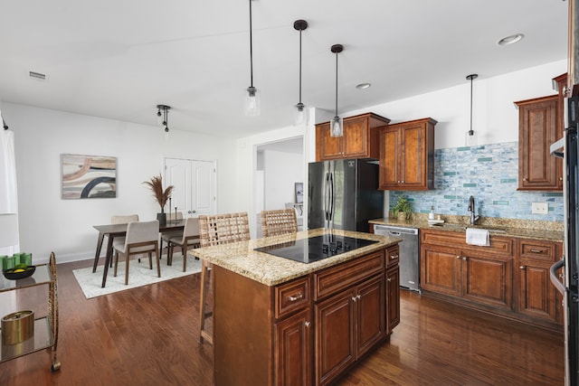 kitchen with dark wood-type flooring, pendant lighting, stainless steel appliances, a center island, and sink