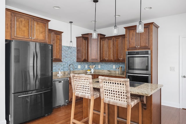 kitchen featuring appliances with stainless steel finishes, hanging light fixtures, a kitchen island, and dark hardwood / wood-style floors