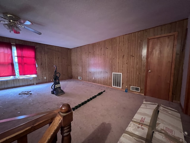 unfurnished room with ceiling fan and wood walls