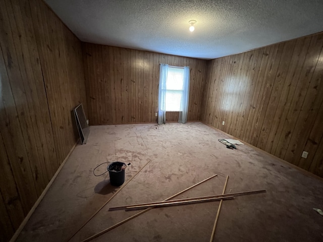 empty room featuring wood walls and a textured ceiling