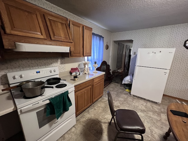 kitchen with exhaust hood, a textured ceiling, and white appliances