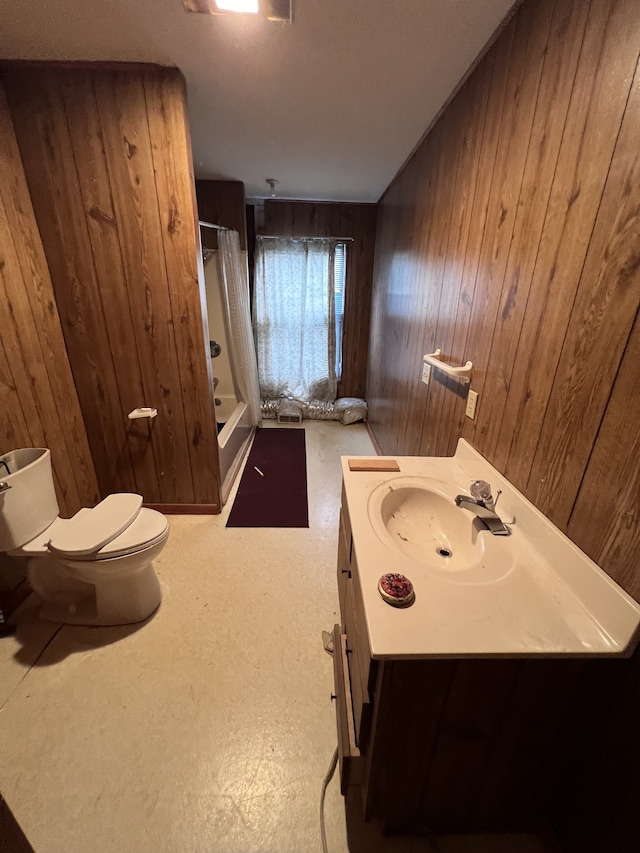 bathroom featuring walk in shower, vanity, wooden walls, and toilet