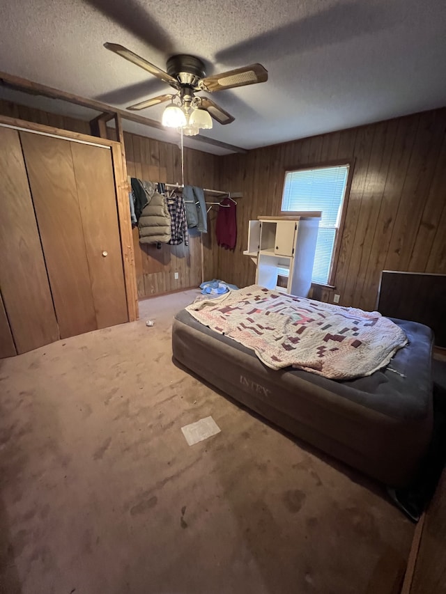 carpeted bedroom with wooden walls, ceiling fan, and a textured ceiling