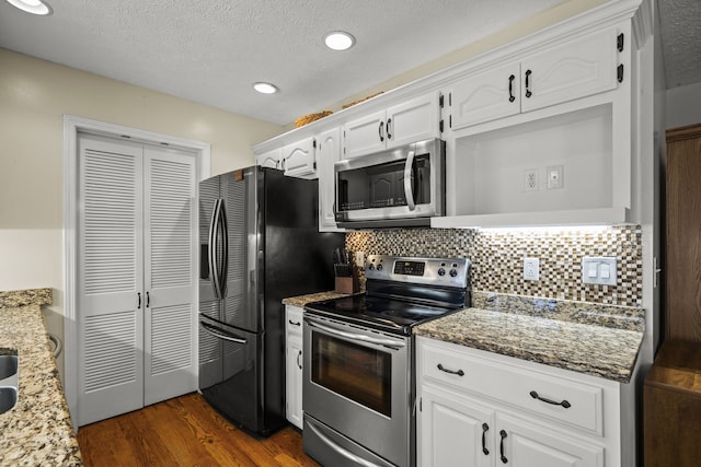 kitchen featuring appliances with stainless steel finishes, white cabinetry, light stone counters, and dark wood-type flooring