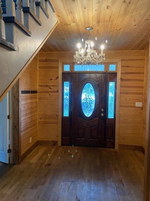 foyer entrance featuring wood-type flooring, wood walls, a chandelier, and wooden ceiling