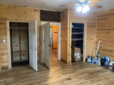 unfurnished bedroom featuring ceiling fan, wooden walls, and hardwood / wood-style floors