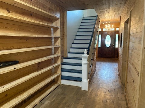 interior space featuring an inviting chandelier, wood ceiling, wood walls, and dark hardwood / wood-style flooring