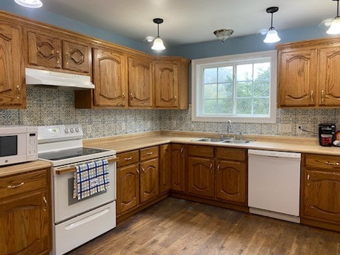 kitchen with sink, white appliances, decorative light fixtures, dark wood-type flooring, and decorative backsplash