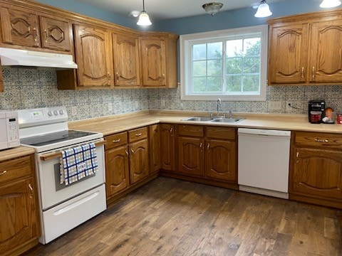 kitchen with sink, white appliances, decorative light fixtures, dark hardwood / wood-style flooring, and decorative backsplash