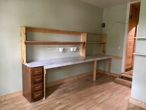 unfurnished office featuring light wood-type flooring and built in desk