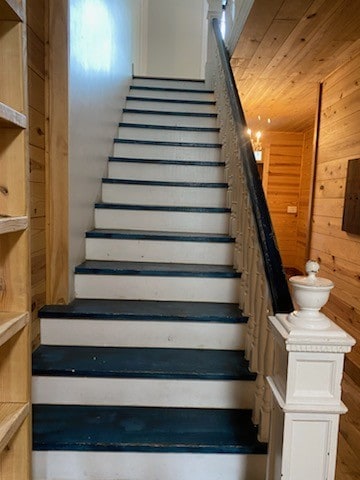 staircase featuring wood walls