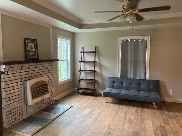 unfurnished living room featuring heating unit, light hardwood / wood-style flooring, a raised ceiling, ornamental molding, and ceiling fan