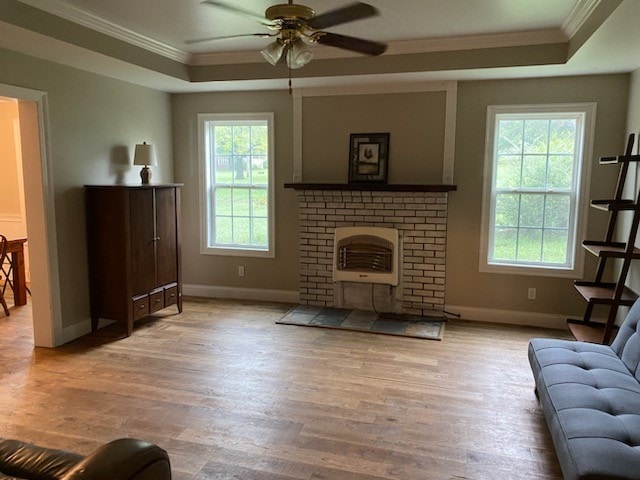 unfurnished living room with ceiling fan, light wood-type flooring, crown molding, and a raised ceiling