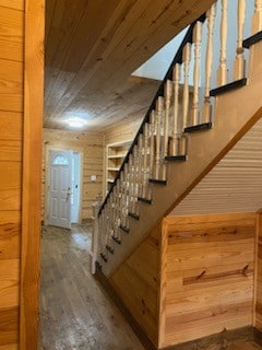 stairs with wooden walls and hardwood / wood-style flooring