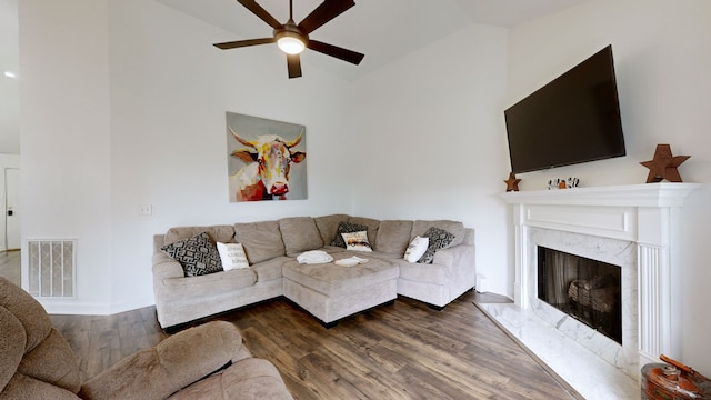 living room featuring vaulted ceiling, ceiling fan, a premium fireplace, and hardwood / wood-style flooring