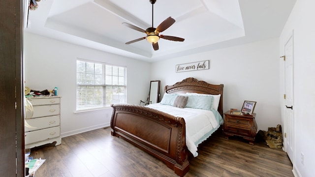 bedroom featuring ceiling fan, a raised ceiling, and dark hardwood / wood-style flooring