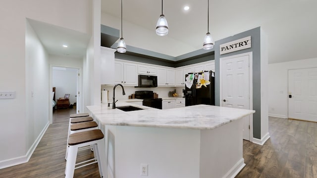 kitchen with light stone counters, sink, white cabinetry, black appliances, and decorative light fixtures