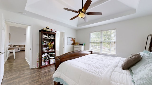 bedroom featuring a tray ceiling, ceiling fan, and dark hardwood / wood-style floors