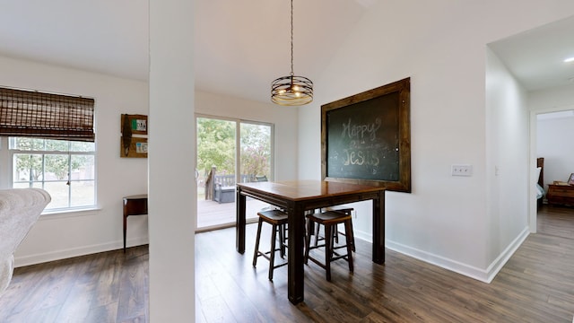 dining area with a notable chandelier, lofted ceiling, and dark hardwood / wood-style flooring