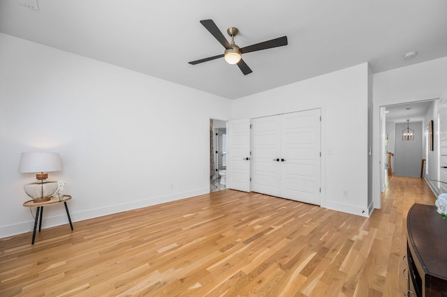 bedroom with ceiling fan with notable chandelier, light wood-type flooring, and a closet