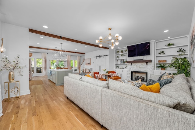 living room featuring light hardwood / wood-style floors, a fireplace, an inviting chandelier, and built in shelves