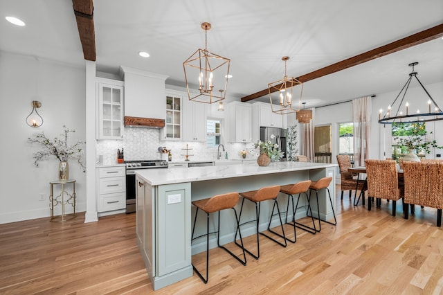 kitchen with white cabinets, beam ceiling, appliances with stainless steel finishes, and custom range hood