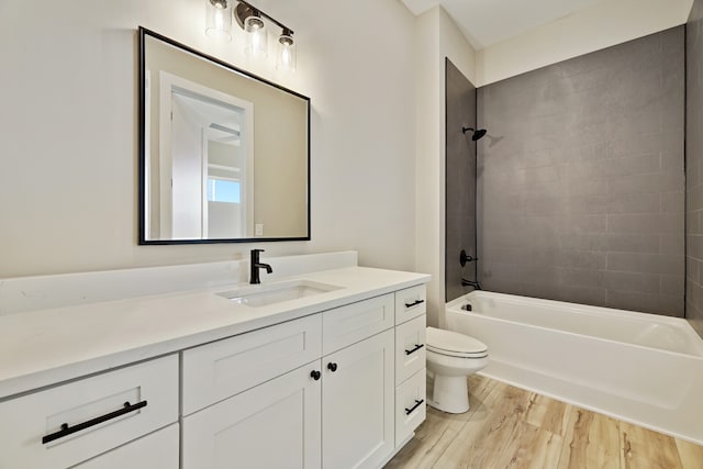 full bathroom with wood-type flooring, vanity, tiled shower / bath combo, and toilet