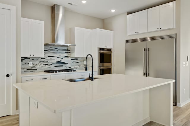 kitchen featuring stainless steel appliances, white cabinetry, a center island with sink, and sink