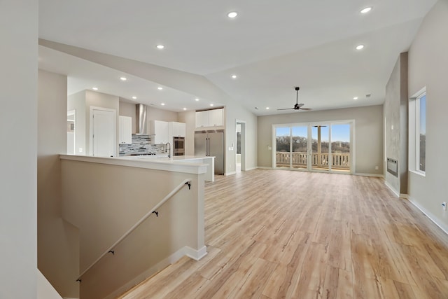 unfurnished living room featuring ceiling fan, lofted ceiling, and light wood-type flooring