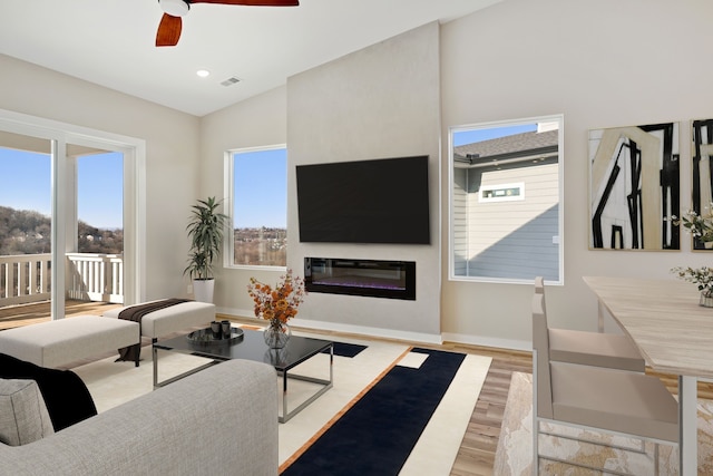 living room featuring light hardwood / wood-style floors, vaulted ceiling, and ceiling fan