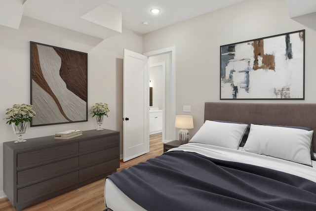 bedroom featuring light wood-type flooring and connected bathroom