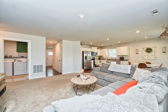 living room featuring carpet, separate washer and dryer, and sink