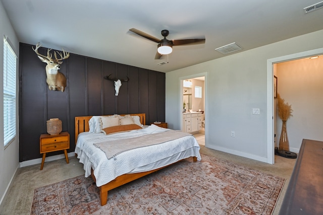 bedroom featuring ensuite bath, ceiling fan, and light colored carpet