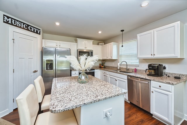 kitchen featuring dark wood-type flooring, sink, white cabinetry, a kitchen island, and appliances with stainless steel finishes