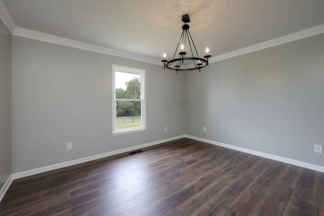 empty room featuring dark hardwood / wood-style flooring, ornamental molding, and an inviting chandelier