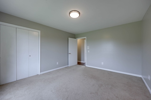 unfurnished bedroom featuring light carpet and a closet