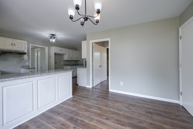 kitchen with light stone countertops, dark wood-type flooring, pendant lighting, white cabinets, and a chandelier